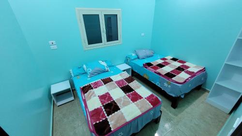 um quarto azul com duas camas e uma janela em Ahmed House em Safaga