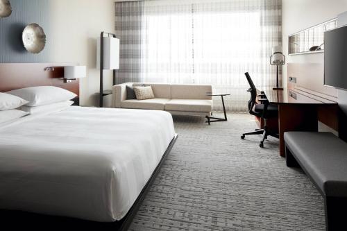 a hotel room with a large bed and a desk at Marriott Montreal Airport In-Terminal Hotel in Dorval