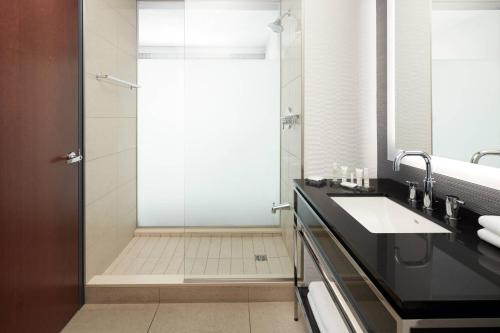 a bathroom with a shower and a sink and a mirror at Marriott Montreal Airport In-Terminal Hotel in Dorval