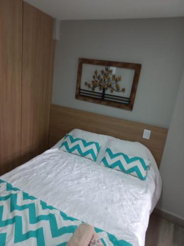 a bed with blue and white pillows on it at Flat Beverly Hills 101A in Vila Velha