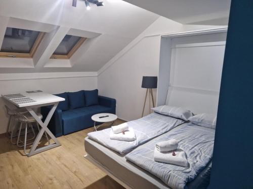 a bedroom with a bed and a desk and a blue couch at Ancora apartment 5 in Novi Sad