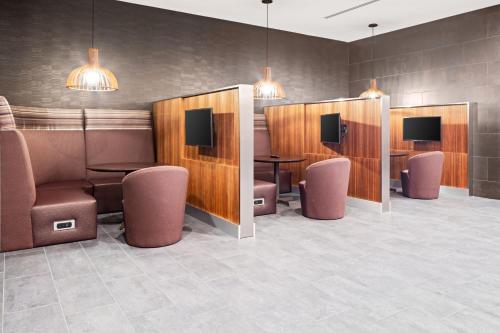 a waiting room with chairs and tables and televisions at Courtyard by Marriott Houston Northeast in Houston