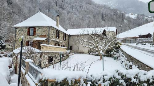 a house covered in snow in a yard at Chambres d'hôtes Les Marmottes in Arbéost