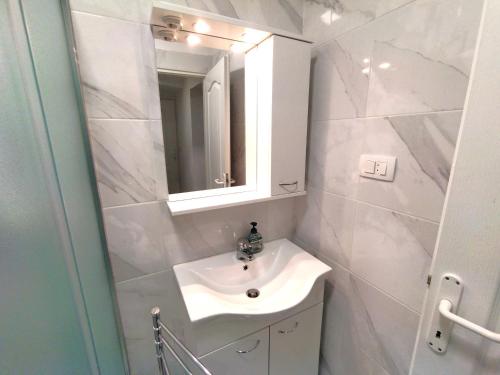 een witte badkamer met een wastafel en een spiegel bij Good Vibrations Apartments in Zagreb