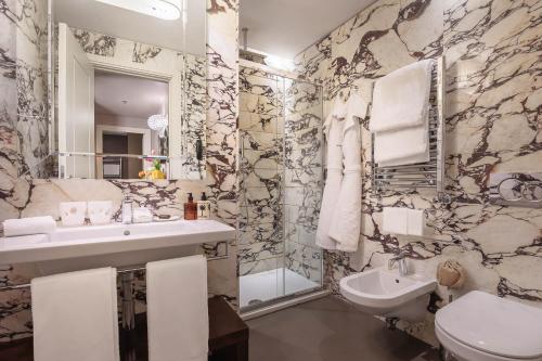 a bathroom with a sink and a toilet and a mirror at Singer Palace Hotel in Rome