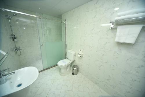 a bathroom with a shower and a toilet and a sink at Alain Hotel Apartments Ajman in Ajman 