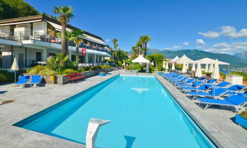 a pool at a resort with blue chairs and umbrellas at Hotel La Campagnola - Green Energy Resort in San Nazzaro