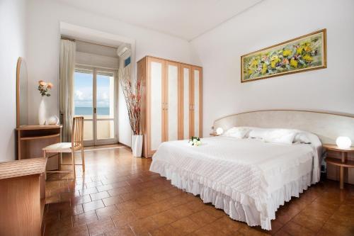 1 dormitorio con cama blanca, mesa y ventana en Hotel Continental, en Gatteo a Mare