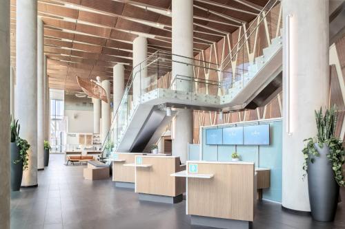 a lobby with a staircase and tables and potted plants at Civic Hotel, Autograph Collection in Surrey