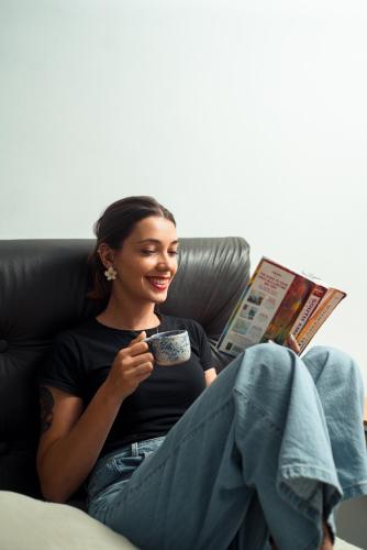 a woman sitting on a couch holding a cup of coffee at Bella 269 Guest house in Santiago