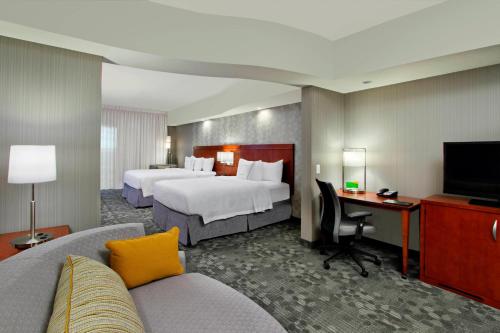 a hotel room with two beds and a tv at Courtyard by Marriott Victoria in Victoria