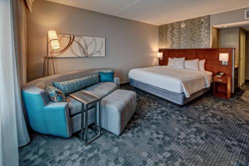 a hotel room with a bed and a couch at Courtyard Newport News Airport in Newport News