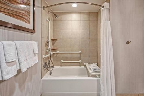 a bathroom with a tub and a shower with towels at Courtyard Newport News Airport in Newport News