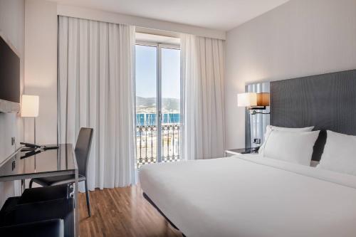um quarto de hotel com uma cama grande e uma janela grande em AC Hotel Palacio Universal by Marriott em Vigo