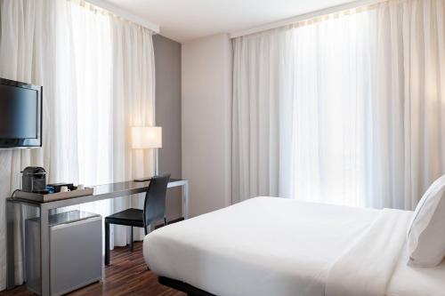 a hotel room with a bed and a desk with a television at AC Hotel Palacio Universal by Marriott in Vigo