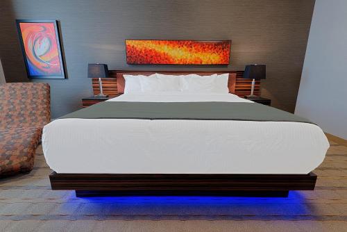 a bedroom with a large white bed and a chair at Hotel Clique Calgary Airport in Calgary