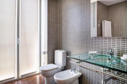 a bathroom with a white toilet and a sink at AC Hotel Palacio Universal by Marriott in Vigo