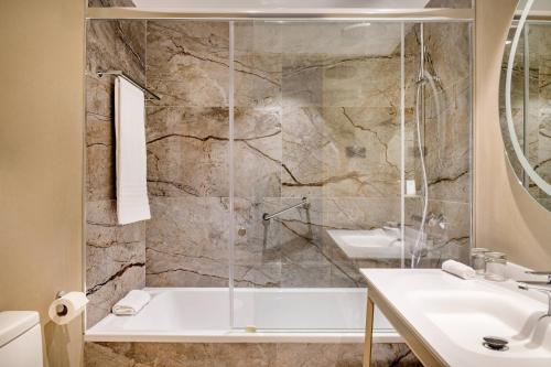 uma casa de banho com um chuveiro, uma banheira e um lavatório. em AC Hotel by Marriott Tenerife em Santa Cruz de Tenerife
