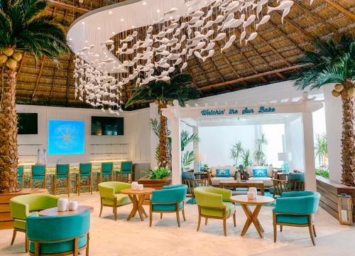 Margaritaville Island Reserve Riviera Cancún - An All-Inclusive Experience for All في بويرتو موريلوس: مطعم فيه كراسي وطاولات وثريا