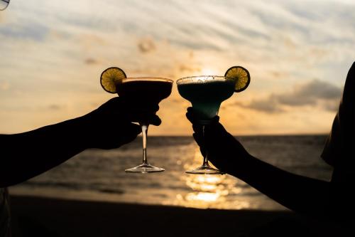 two people holding wine glasses in front of the ocean at Margaritaville Island Reserve Riviera Cancún - A Karisma All-Inclusive Experience for All in Puerto Morelos