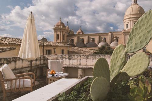 a patio with a table and a white umbrella and cactus at Palazzo Trigona Suites in Noto