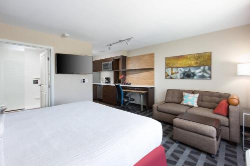 a hotel room with a bed and a couch and a desk at TownePlace Suites By Marriott Las Vegas Stadium District in Las Vegas