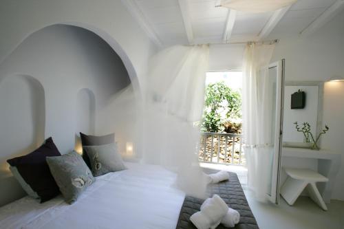 Un dormitorio con una gran cama blanca y una ventana en NINEMIA CALM AND SPA, en Kionia