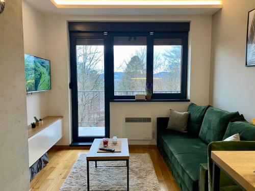 a living room with a green couch and a table at EVA apartman, Titova Vila, Zlatibor in Palisad