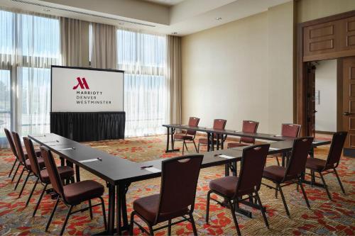 a conference room with tables and chairs and a screen at Denver Marriott Westminster in Westminster