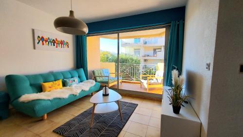 uma sala de estar com um sofá verde e uma varanda em Appartement à 100m de la plage 7 nuits minimum haute saison em Sainte-Maxime