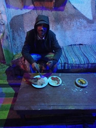 a man sitting on a table with plates of food at Caravan Nights in desert in Dahab