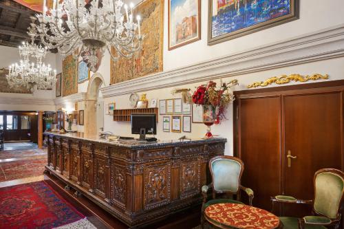 a lobby with a wooden bar with chairs and a chandelier at Residenza d'Epoca San Cassiano in Venice