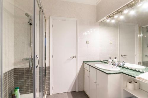 La salle de bains blanche est pourvue d'un lavabo et d'une douche. dans l'établissement Amplio y Cómodo en Basurto, à Bilbao