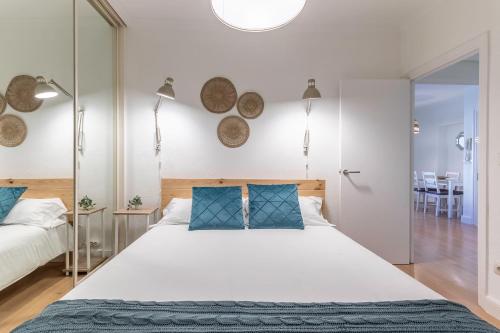 - une chambre avec un grand lit blanc et des oreillers bleus dans l'établissement Amplio y Cómodo en Basurto, à Bilbao