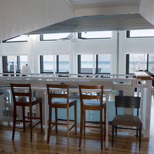 a kitchen with a bar with chairs and windows at The Purple Martin Lakeside Inn Bird Sanctuary on Lake Huron in Rogers City