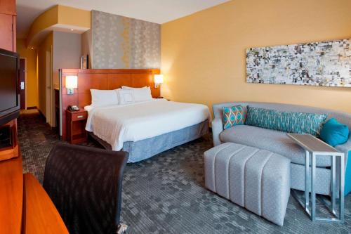une chambre d'hôtel avec un lit et un canapé dans l'établissement Courtyard Minneapolis Maple Grove Arbor Lakes, à Maple Grove
