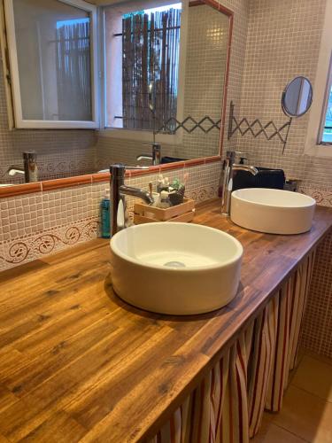 uma casa de banho com 2 lavatórios num balcão de madeira em Villa des Oliviers em Baillargues