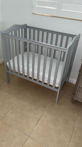 a grey crib sitting in a room with a tile floor at House w/ heated pool in Naples 5 min to beach in Naples