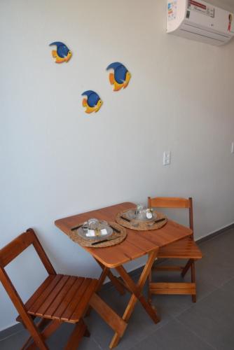 a wooden table with two chairs and a table with birds on the wall at Residencial Lucernaré - Resende in Itacaré