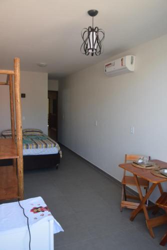 a room with a bed and a table and a desk at Residencial Lucernaré - Resende in Itacaré