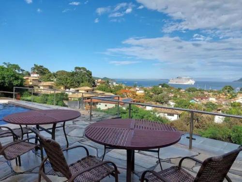 a balcony with a table and chairs and a cruise ship at Casa Espetacular - João Fernandes - NÃO ACEITAMOS PETS in Búzios