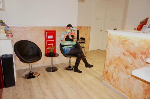 a woman sitting in a chair reading a newspaper at MuchoMadrid in Madrid