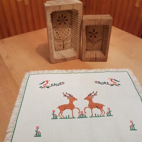 a table with two wooden boxes and a rug with deer on it at Miklavževa hiša with a bread oven in Železniki