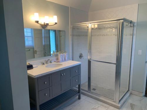 a bathroom with a shower and a sink and a mirror at Beach Walk Cottage in Mount Pleasant
