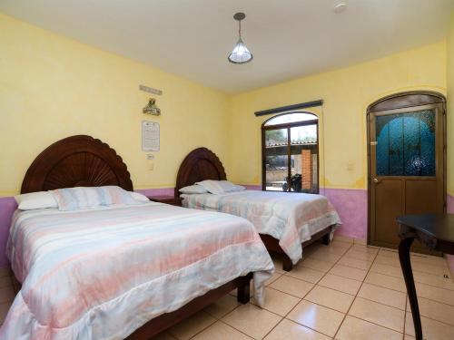 Duas camas num quarto com paredes amarelas em Hotel Quinta Mirador Zacualli em Bernal