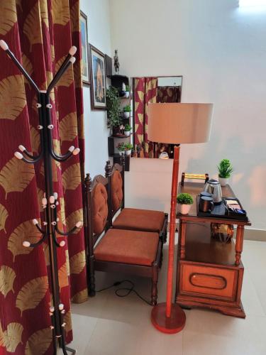 a room with a chair and a table with a lamp at Dhairya's Villa Home Away From Home in Jammu