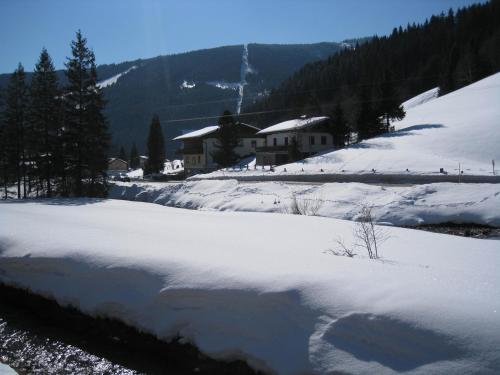 a snow covered field with houses in the background at Haus Filzmoos in Filzmoos