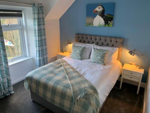 1 dormitorio con 1 cama con una foto de pingüino en la pared en Burnbank BnB, en Tobermory