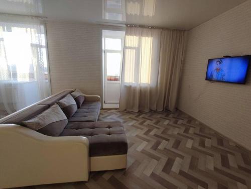 uma sala de estar com um sofá e uma televisão de ecrã plano em Апартаменты в новостройке по Байзакова 131/1 em Pavlodar