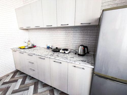 uma cozinha com armários brancos e uma bancada em mármore em Апартаменты в новостройке по Байзакова 131/1 em Pavlodar